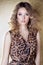 Beautiful girl in leopard dress in bright makeup in the Studio on a gold background