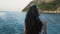 A beautiful girl letting her long brown hair down in front of the river and a mountain. A half-body portrait