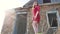 Beautiful girl lifestyle in a red dress. girl in a dress is standing next to the old house of the ruins