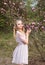 Beautiful girl in a light lilac dress in the garden where magnolias bloom