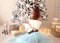 A beautiful girl like Cinderella in a Christmas fairy tale sits near a Christmas tree and examines Christmas balls