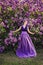 Beautiful girl in lilac ball dress among the flowers