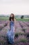 Beautiful girl in a long dress walking in a lavender field at sunset. Soft focus