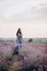 Beautiful girl in a long dress walking in a lavender field at sunset. Soft focus