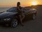 Beautiful girl with long hair posing beside a cabriolet on sunset