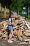 beautiful girl with long hair in white T-shirt and denim shorts puts firewood in pile.