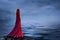 Beautiful girl in a long red dress stands by the river with fog