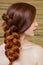 Beautiful girl with long red hair, braided with a French braid, in a beauty salon