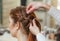 Beautiful girl with long red hair, hairdresser weaves a braid, in a beauty salon