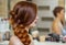 Beautiful girl, with long, red-haired hairy. hairdresser weaves a French braid