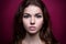 Beautiful girl looking at the camera.Shoot at studio. On a pink background. Strong face. Iris eyes. Portrait young woman.