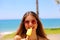 Beautiful girl looking to the side with sunglasses eating popsicle on Malaga beach in her travel holidays in Southern Spain