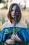 Beautiful girl with a lupine flower in her hands in a field at sunset covers her face