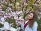 Beautiful girl among magnolia pink blossom sping tree flowers