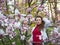 Beautiful girl among magnolia pink blossom sping tree flowers