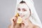 Beautiful girl makes fruit cosmetic face mask. Attractive girl with spa mask smiling and holding citrus fruit