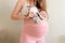 A beautiful girl in the ninth month of pregnancy is holding small gray socks for a newborn.