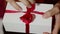 Beautiful girl opens her gift. Beautiful hands of a girl open a New Year`s gift, untying a red ribbon. Gift for the holiday. Gift