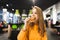 Beautiful girl in a orange hoodie bites an appetizing burger against the background of a fast-food restaurant