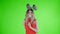 Beautiful girl in party hat and cardboard mustache is dancing on a green screen