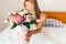 Beautiful girl with peony flowers sitting on the bed. She just w