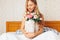 Beautiful girl with peony flowers sitting on the bed. She just w