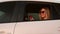 A beautiful girl with a phone in her hands rides in a car and looks out the window. Beautiful young girl in sunglasses
