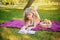 Beautiful girl on a picnic in the park is reading a book. Blonde on a purple bedspread resting. Fruit basket at a picnic