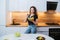 A beautiful girl with a plate of diet salad stands in the kitchen. Woman eating vegetarian salad with herbs