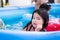 Beautiful girl playing in a blue rubber pool with her siblings. Child looks at the camera.