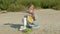 A beautiful girl plays on a ukulele on the river bank near a tourist tent