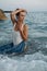 Beautiful girl posing in the sea waves in evening. fashion photo shoot in nature