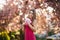 Beautiful girl posing to the photographer against the background of blooming pink trees. Spring. Sakura.