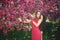 Beautiful girl posing to the photographer against the background of blooming pink trees. Spring. Sakura.