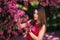 Beautiful girl posing to the photographer against the background of blooming pink trees. Spring. Sakura.