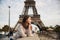 Beautiful girl posing to the photographer against the background of the Eiffel Tower. Autumn photosession. Sunny weather