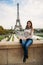 Beautiful girl posing to the photographer against the background of the Eiffel Tower. Autumn photosession. Sunny weather