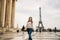 Beautiful girl posing to the photographer against the background of the Eiffel Tower. Autumn photosession. Sunny weather