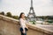 Beautiful girl posing to the photographer against the background of the Eiffel Tower. Autumn photosession. Sunny weather