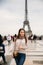 Beautiful girl posing to the photographer against the background of the Eiffel Tower. Autumn photosession. Sunny weather