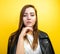 Beautiful girl posing yellow background. Portrait of a young girl with open mouth in a black leather jacket