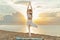 Beautiful girl practices yoga at dawn on seashore. Woman in tree pose Vrikshasana on sea background