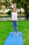 Beautiful girl practices yoga at sunrise on the grass in a park