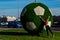 A beautiful girl pushes a big green ball for football. The ball decorates St. Petersburg for the World Cup in 2018