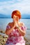 Beautiful girl with radiant red hair in sommer dress in a meditative spiritual gesture of prayer.