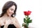 Beautiful girl receives three red roses. She is surprised, looking at the flowers and smiling.