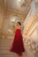 Beautiful girl in a red ball gown in palace interiors