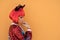 Beautiful girl in red devil costume standing against the wall in anticipation of Halloween. Wears a red wig and horns