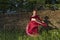 Beautiful girl in red dress dances incendiary dance on summer meadow against of hedge.