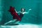 Beautiful girl in a red dress swims under water. amazing Underwater